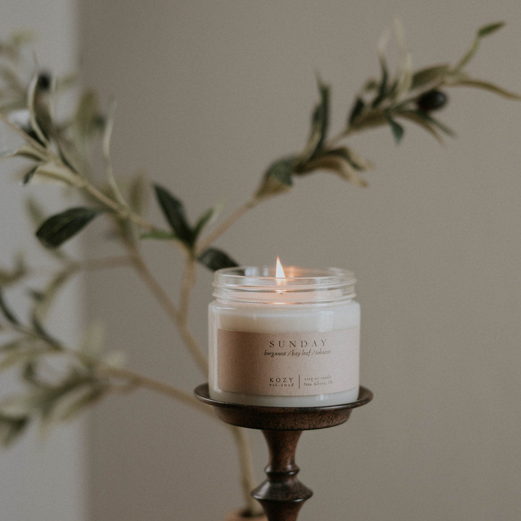 Candle on a holder with olive branches in the background