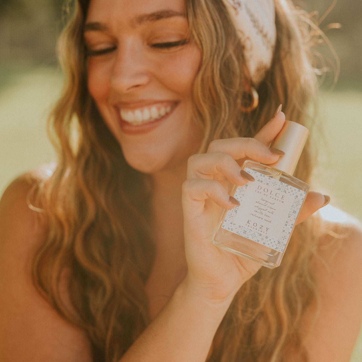 Woman holding a small bottle of perfume outdoors