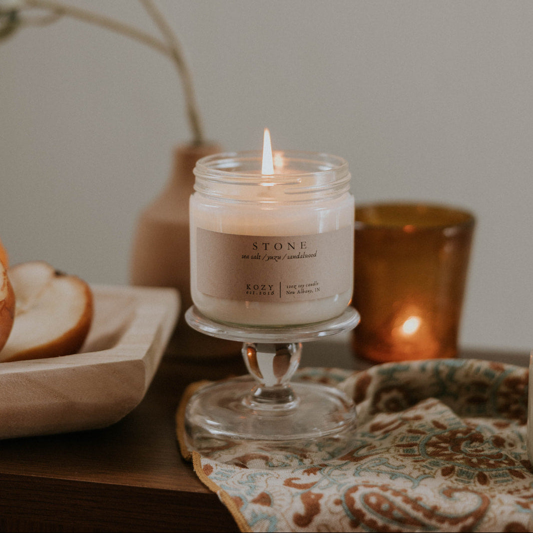 Candle on a small glass stand with a decorative background