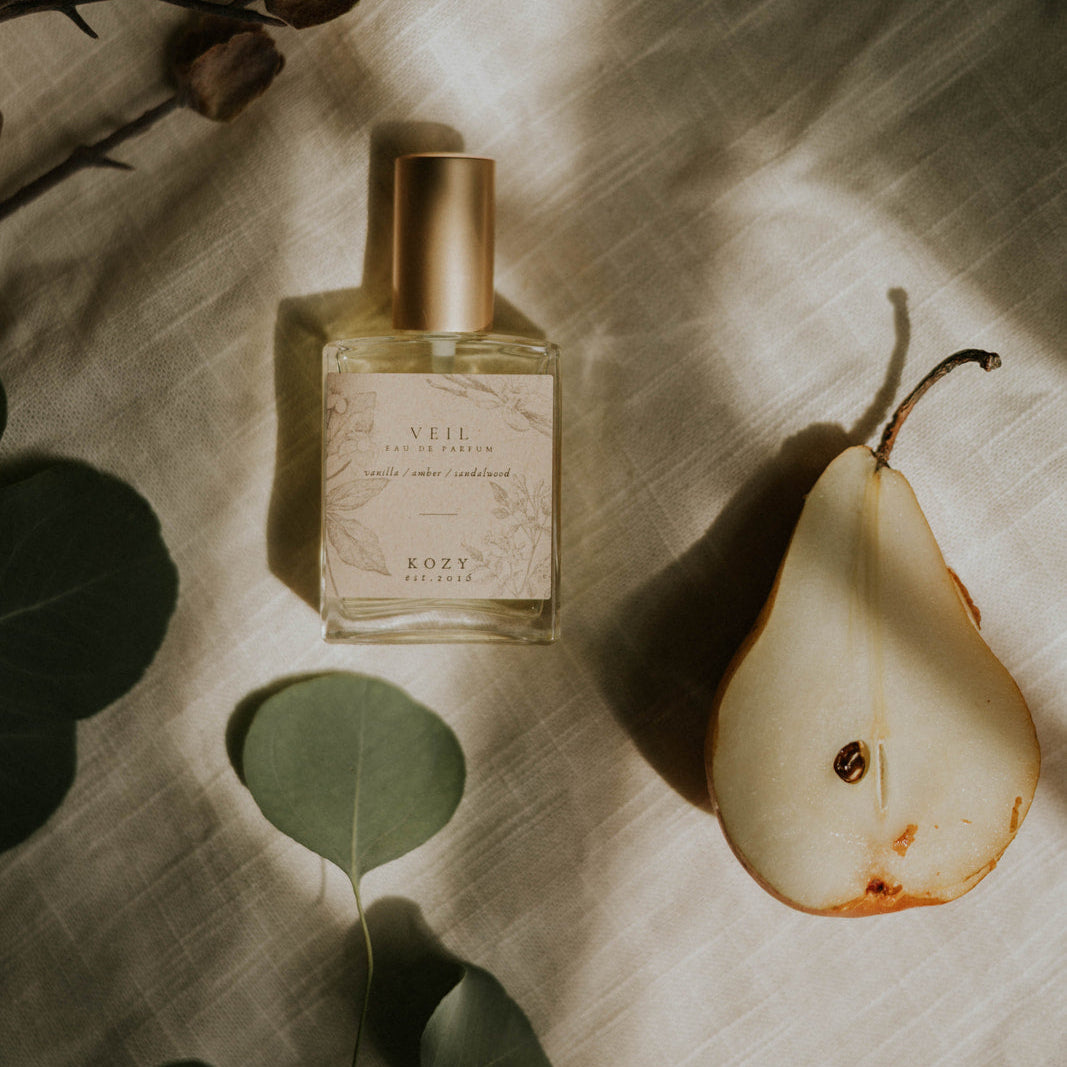 Perfume bottle with a pear and leaves on a textured surface