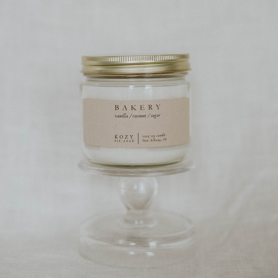 Candle labeled 'Bakery' on a white pedestal against a light background