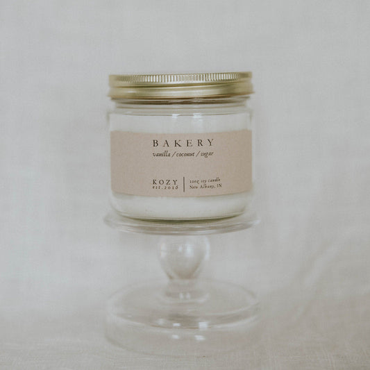 Candle labeled 'Bakery' on a white pedestal against a light background