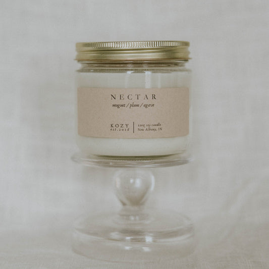 Candle in a glass jar with a gold lid on a light gray background