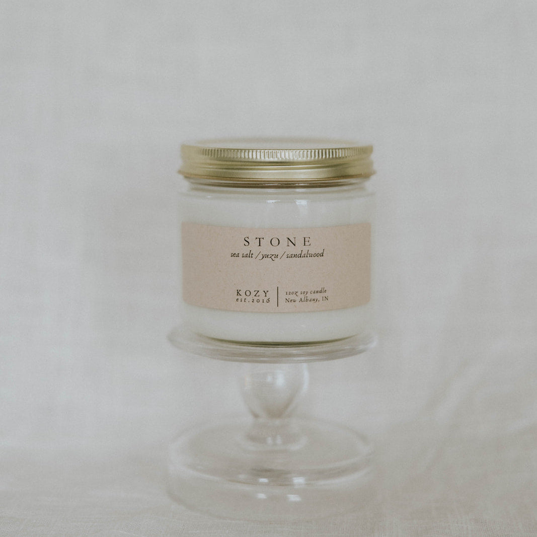 Candle in a glass jar with a gold lid on a white background