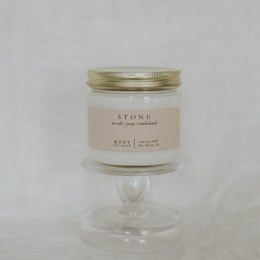 Candle in a glass jar with a gold lid on a white background