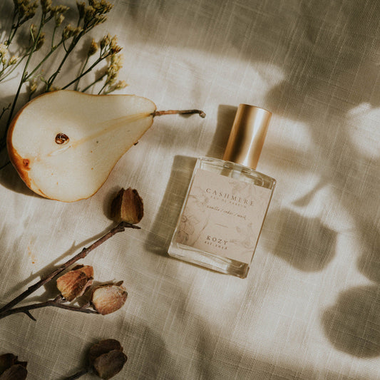 Perfume bottle with a pear and flowers on a textured surface