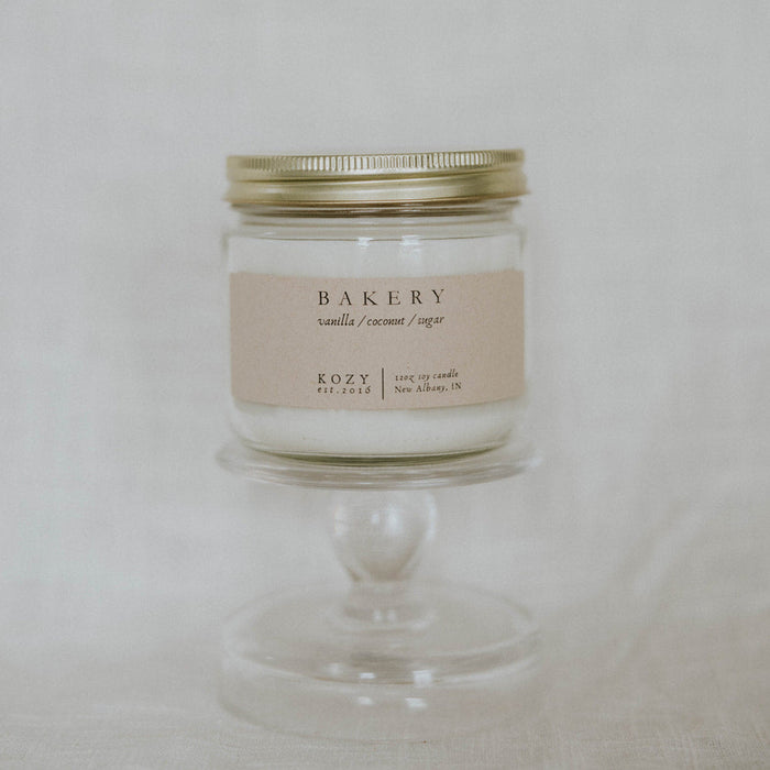 Candle labeled 'Bakery' on a white pedestal against a light background