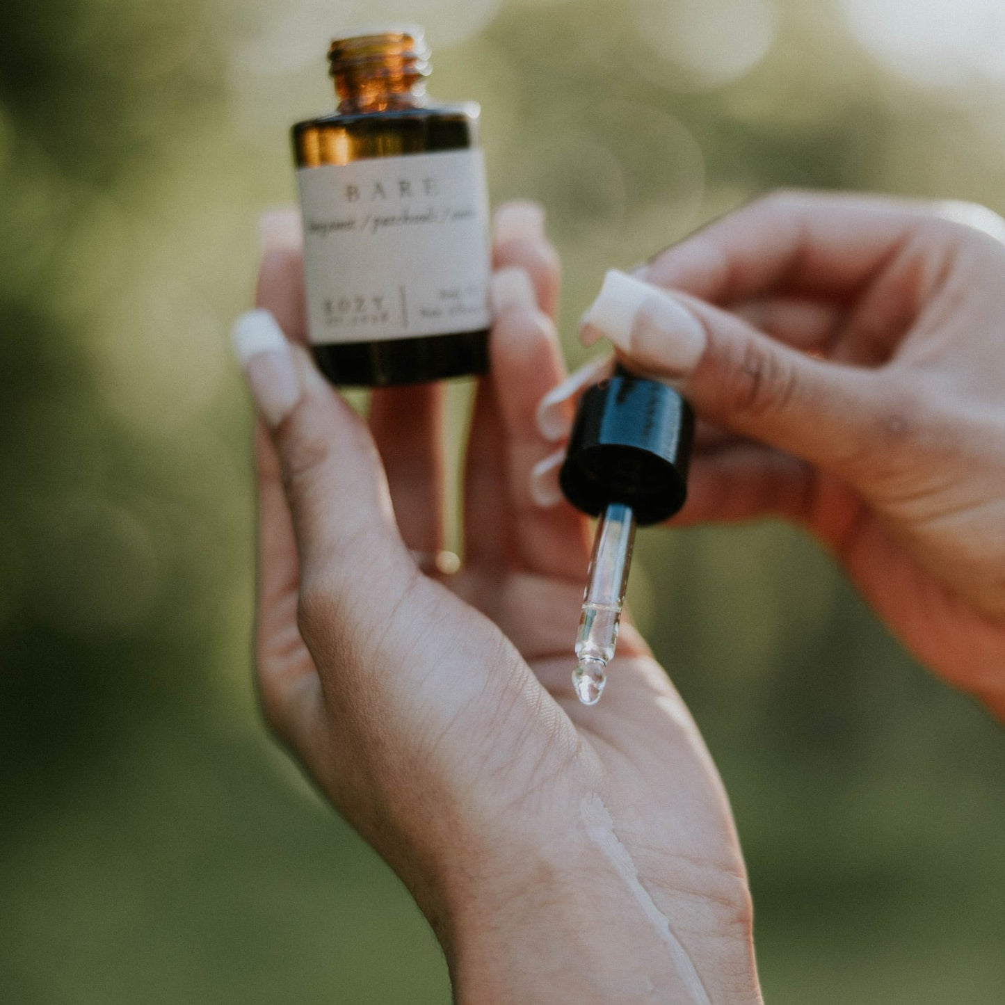 Person holding a dropper bottle with a blurred natural background