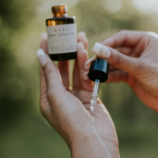Person holding a dropper bottle with a blurred natural background