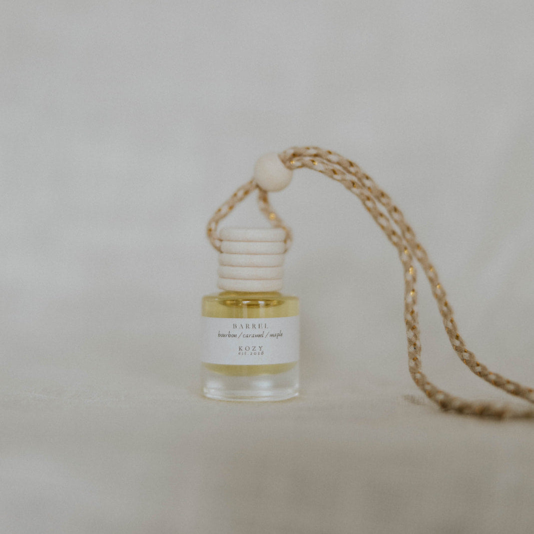 Small hanging car diffuser in the scent 'Barrel' on a beige background