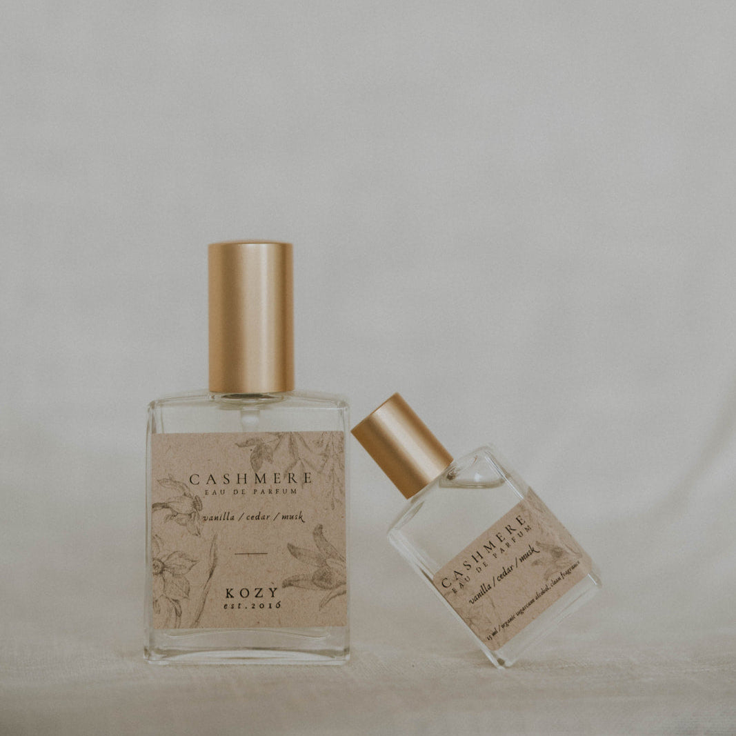 Two perfume bottles with gold caps on a neutral background
