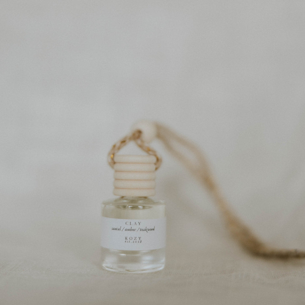Small glass car diffuser in the scent 'Clay' with a neutral background.