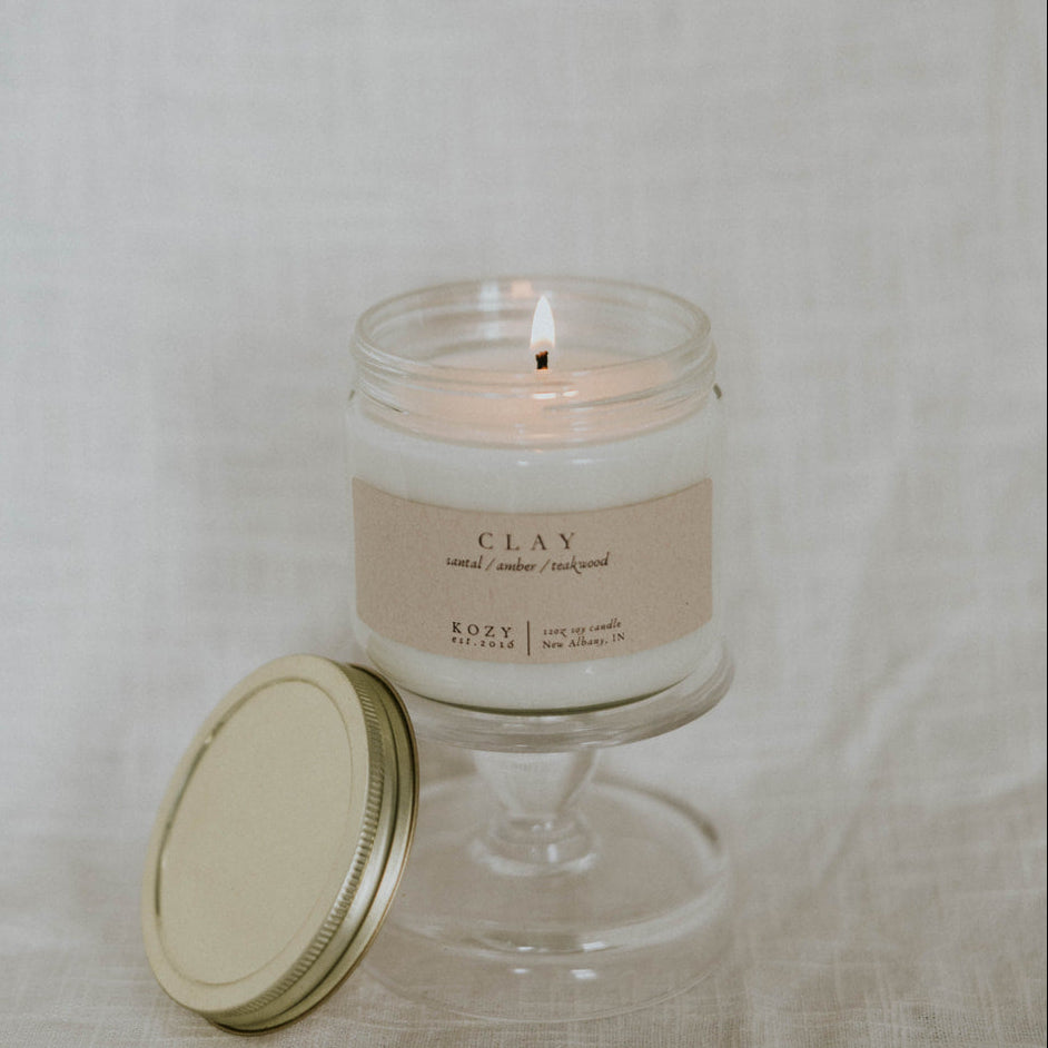 Glass candle with a beige label on a textured beige background