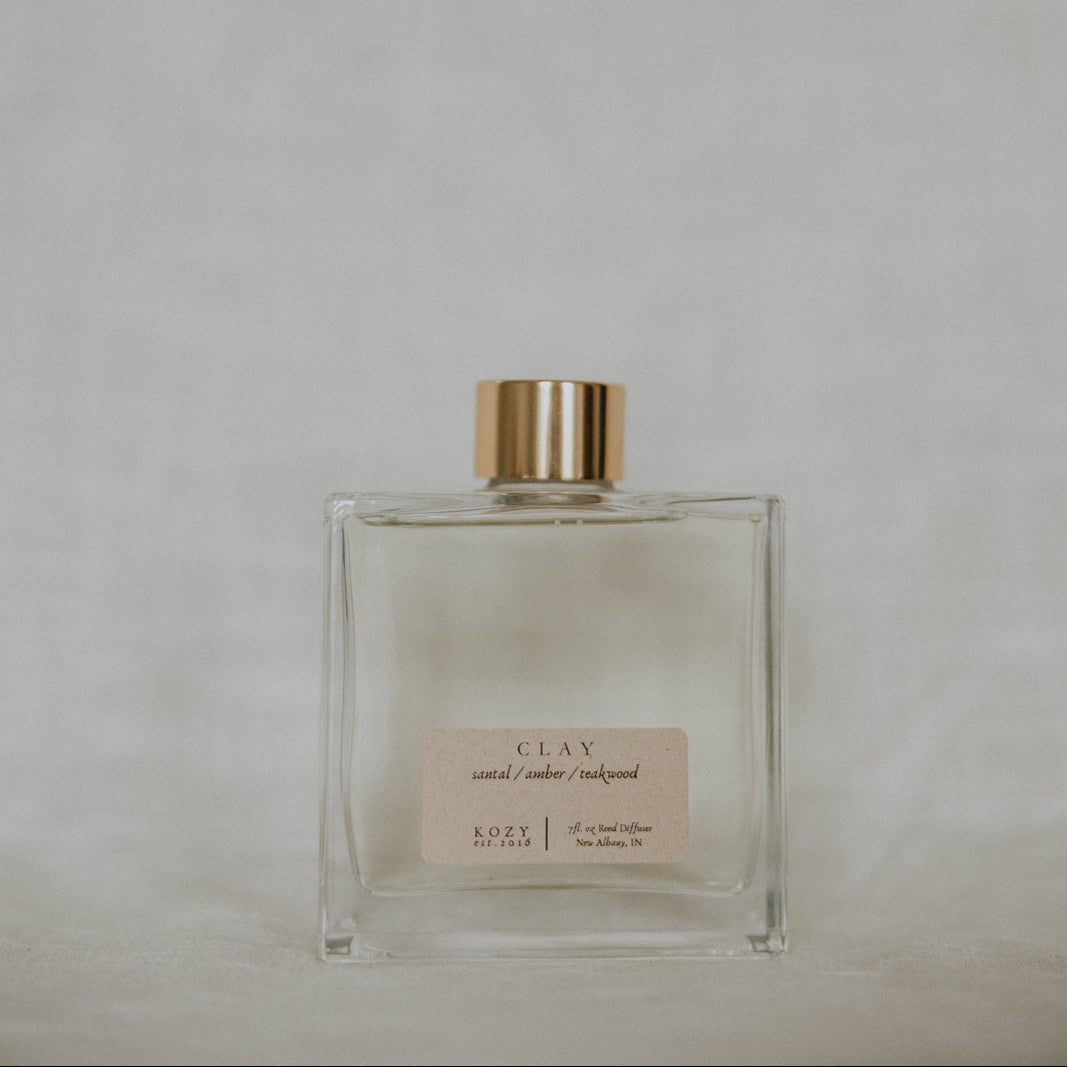 Clear glass bottle with gold cap on a light gray background
