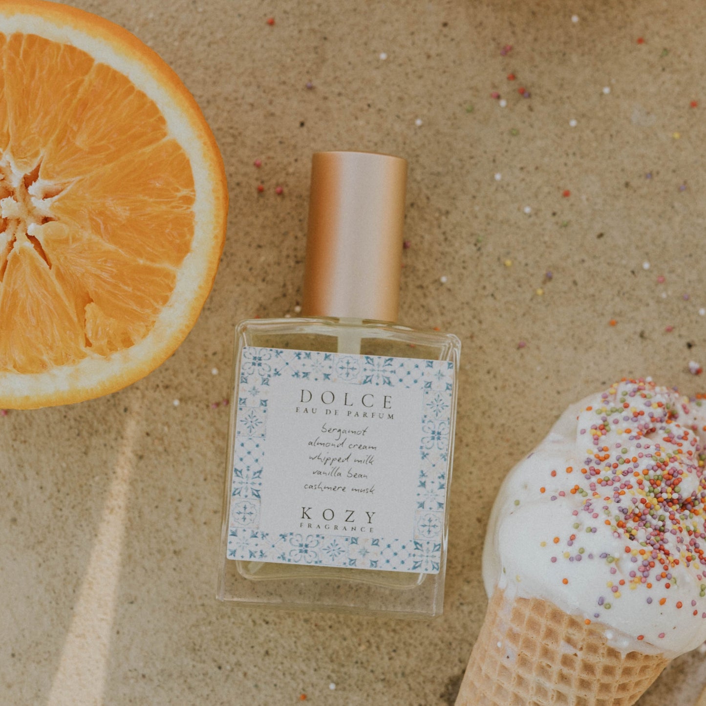 Perfume bottle with oranges and a shell on a textured surface