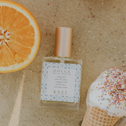 Perfume bottle with oranges and a shell on a textured surface