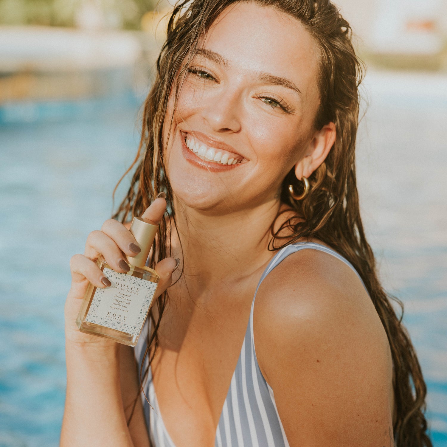 Woman holding a Dolce scented perfume by a pool