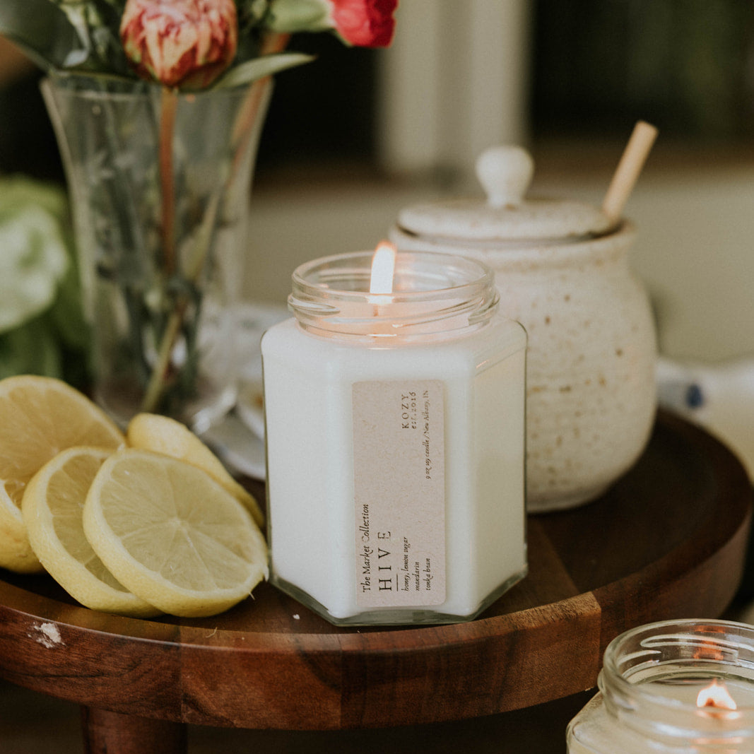Candle on a wooden table with flowers and lemons in the background