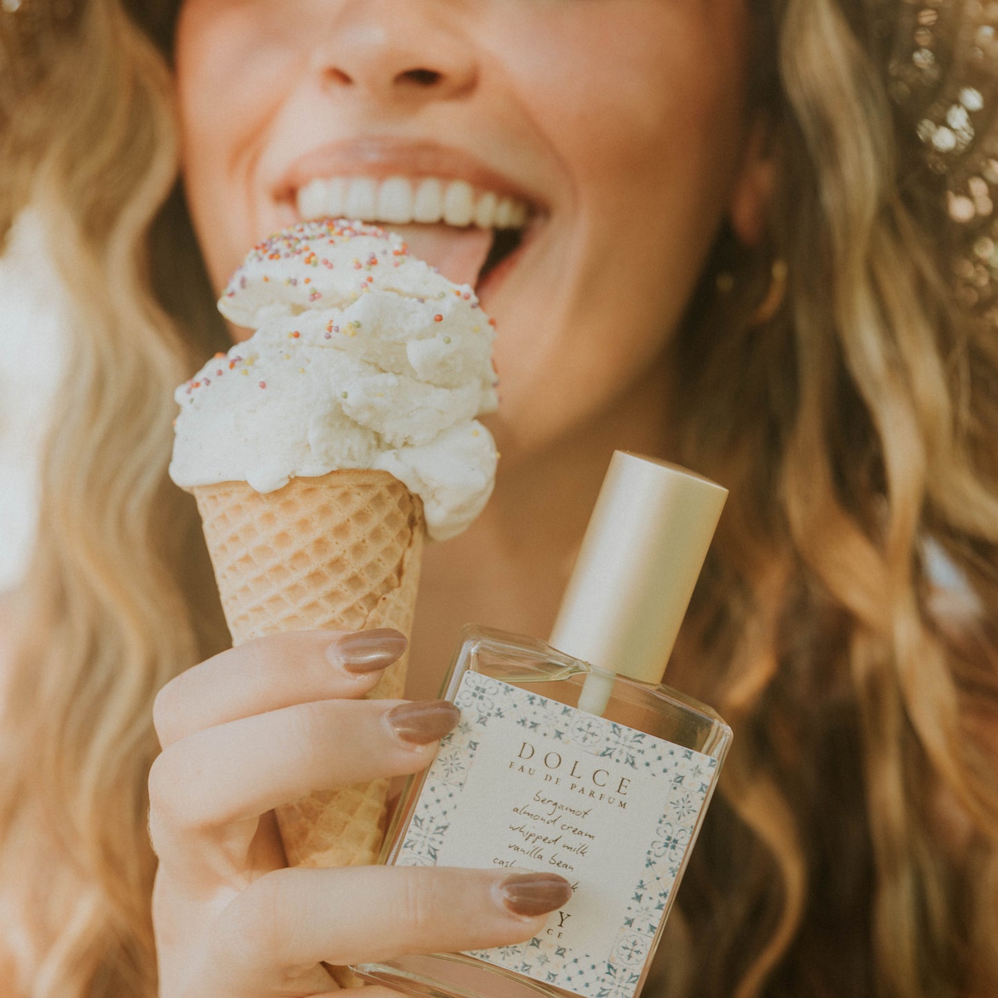 Woman holding a ice cream cone and a Dolce & Gabbana perfume bottle.