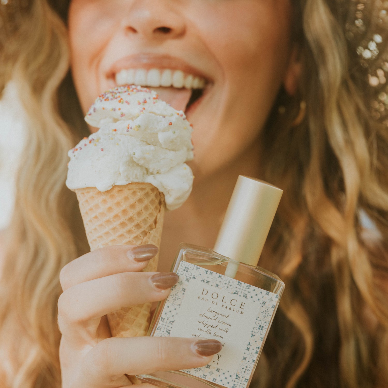 Woman holding a ice cream cone and a Dolce & Gabbana perfume bottle.