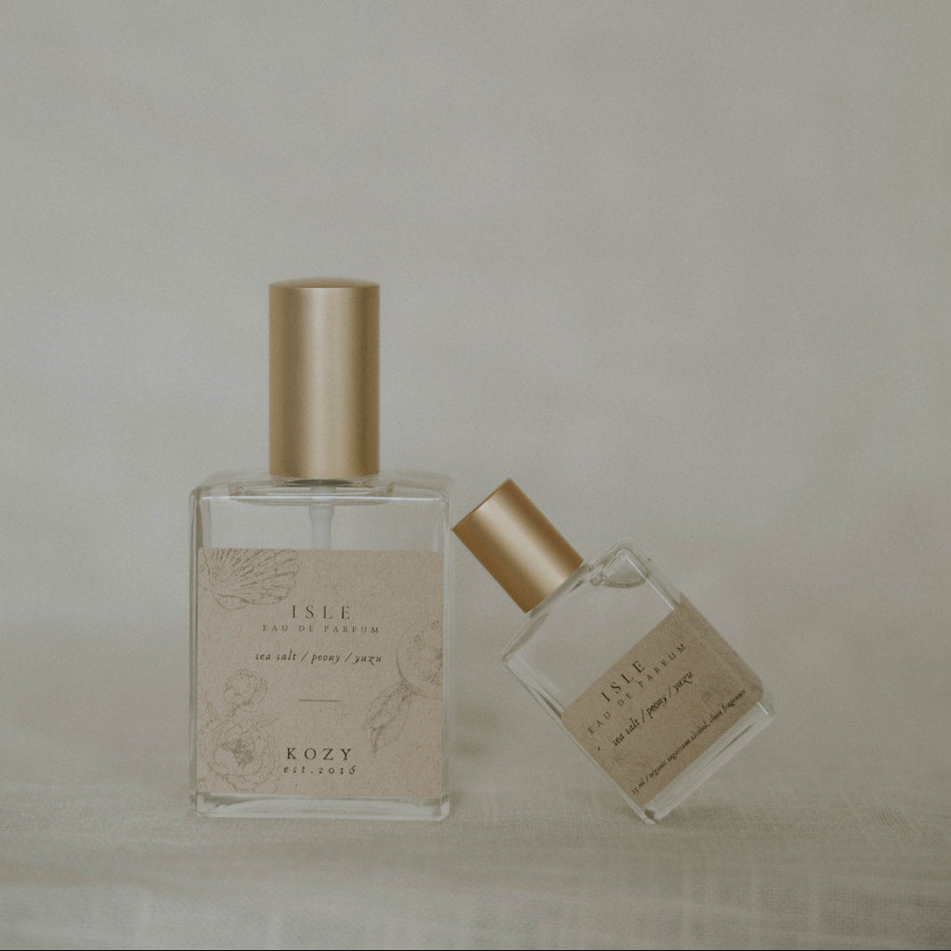 Two perfume bottles with gold caps on a neutral background
