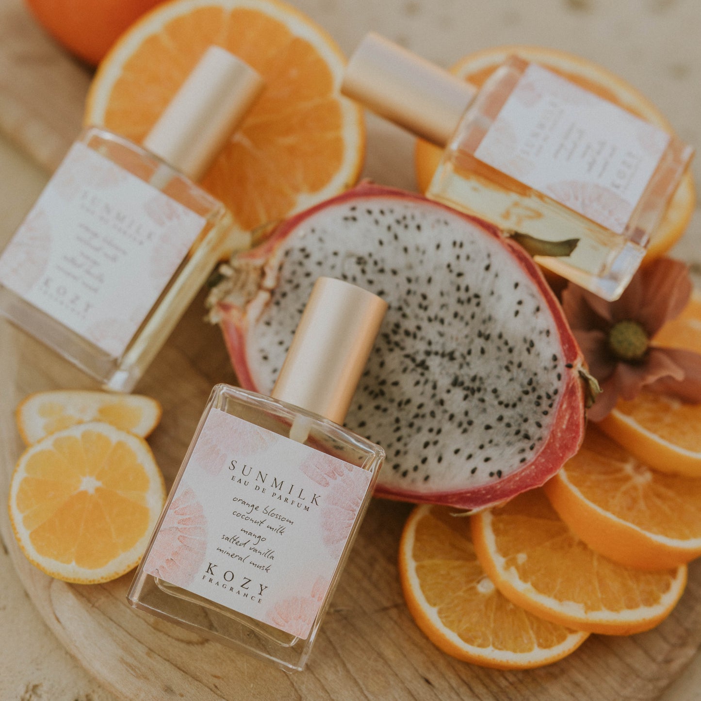 Perfume bottles on a wooden board with dragon fruit and oranges