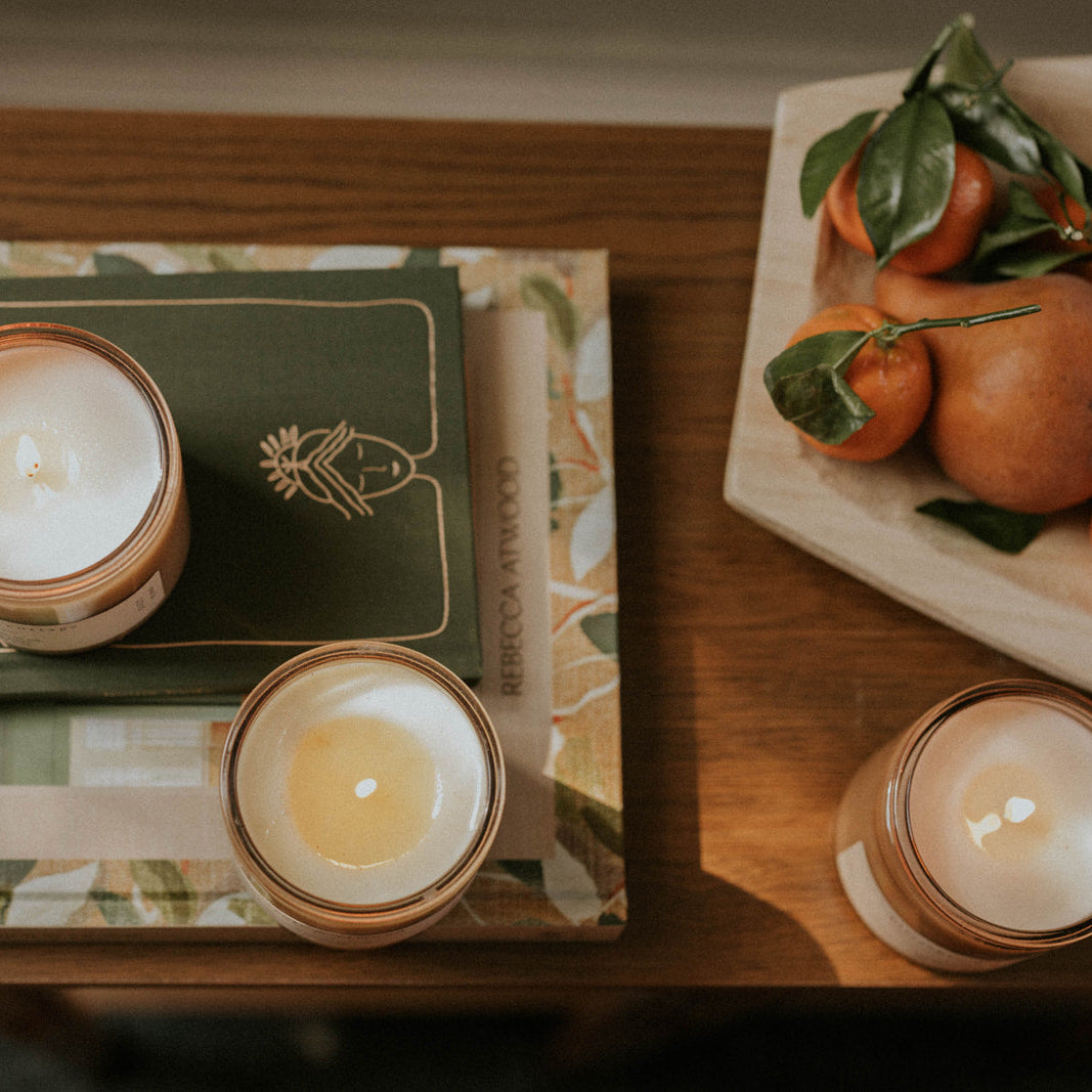 Candlelit scene with books and oranges on a wooden surface