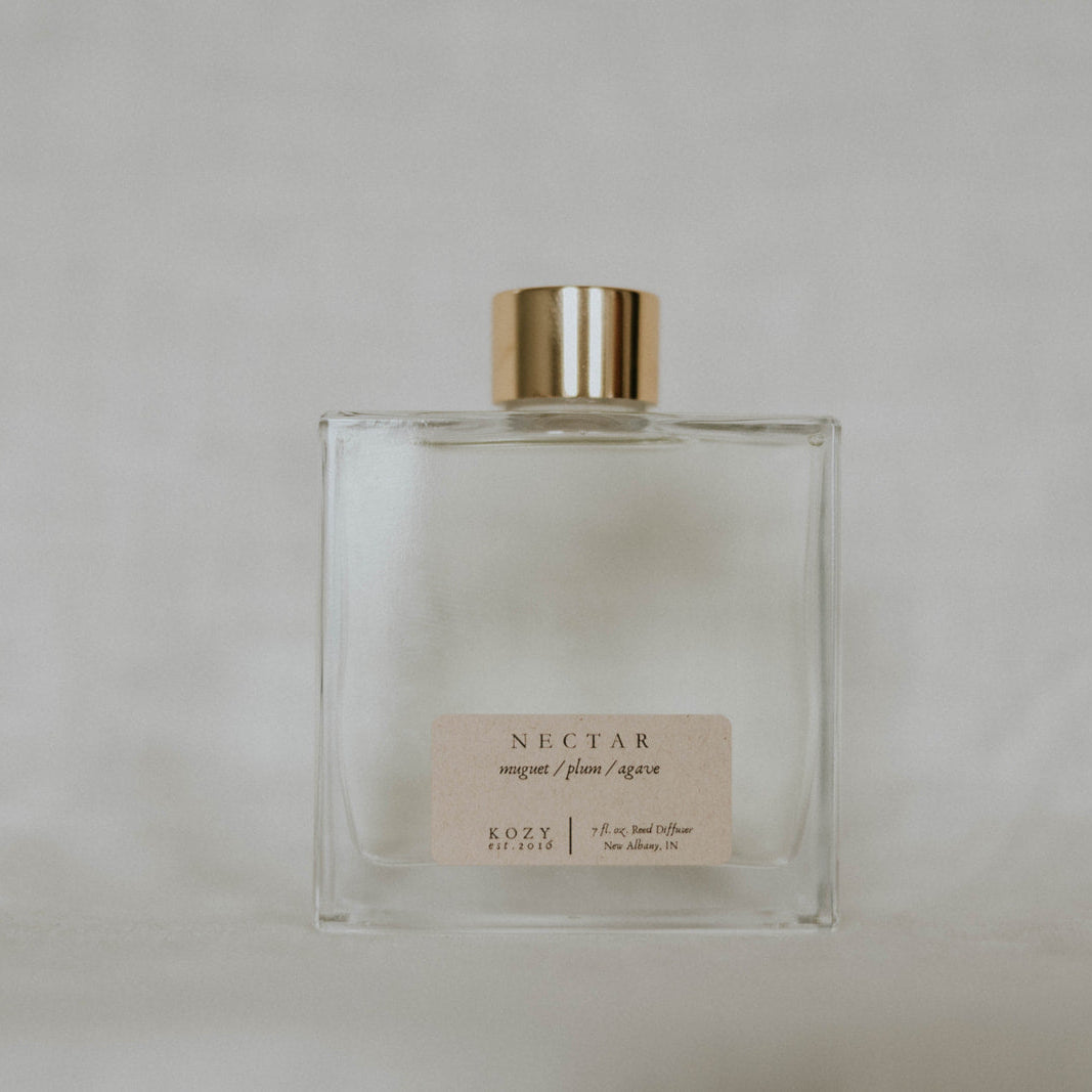 Clear glass bottle with gold cap labeled 'Nectar' on a light gray background