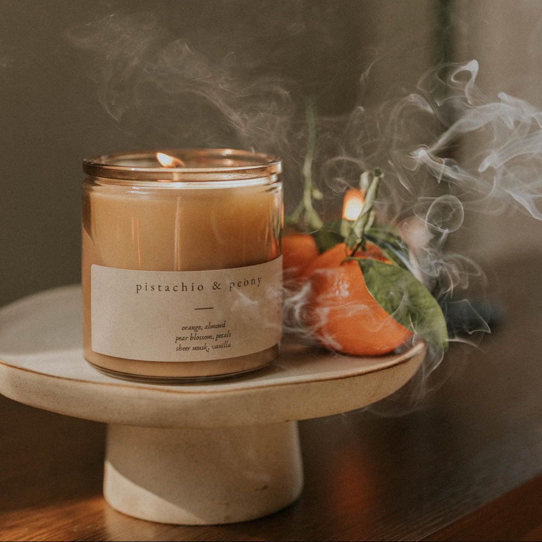 Candle on a white plate with decorative elements and smoke in the background