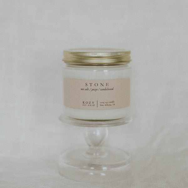 Candle in a glass jar with a gold lid on a white background