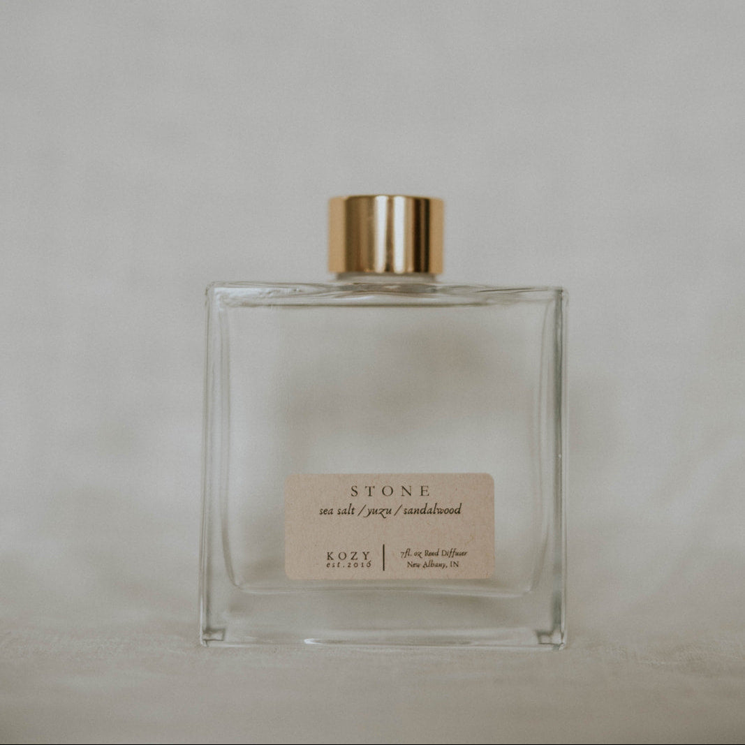 Clear glass bottle with gold cap on a light gray background