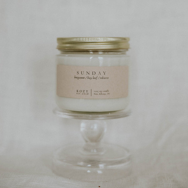 Candle in a glass jar with a gold lid on a white background