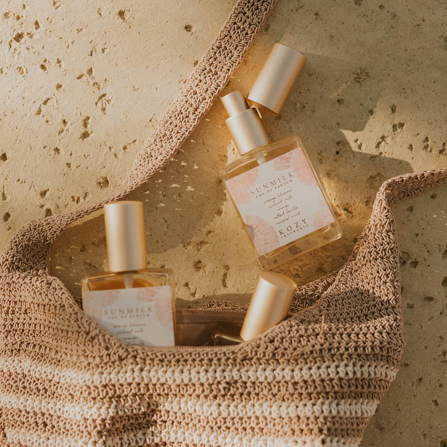 Two perfume bottles on a textured surface with a woven basket.