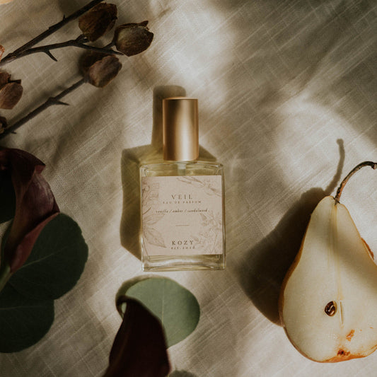Perfume bottle with a pear and flowers on a textured surface