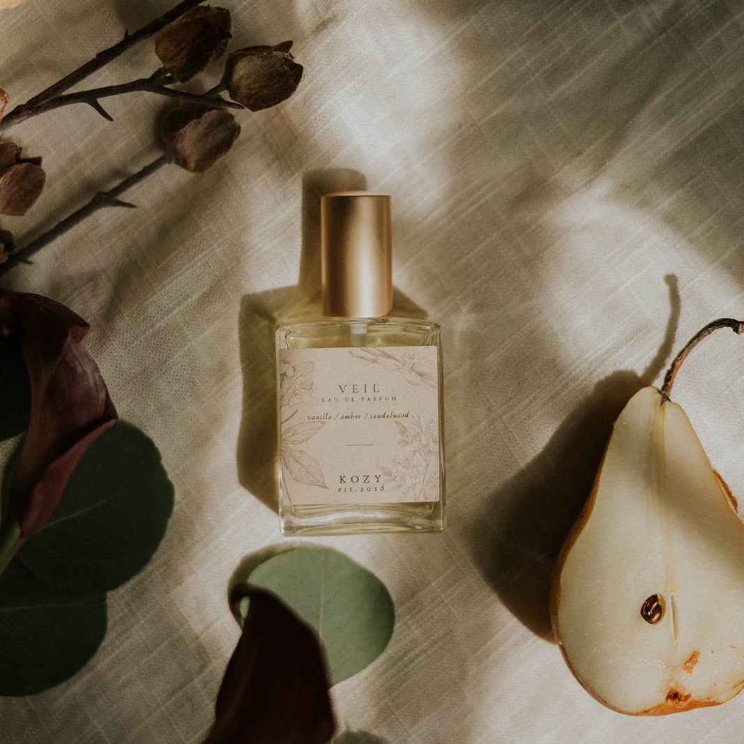 Perfume bottle with a pear and flowers on a textured surface