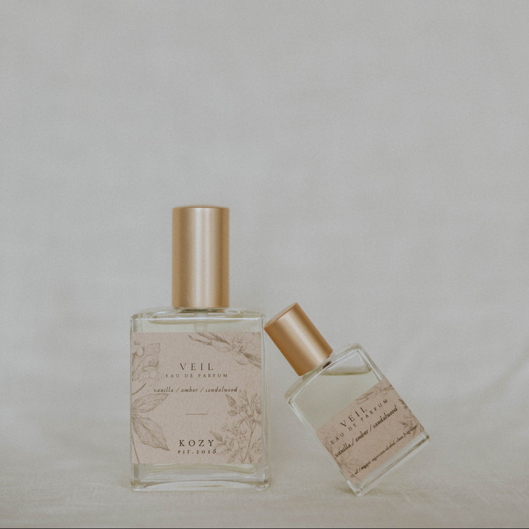 Two perfume bottles with gold caps on a light gray background