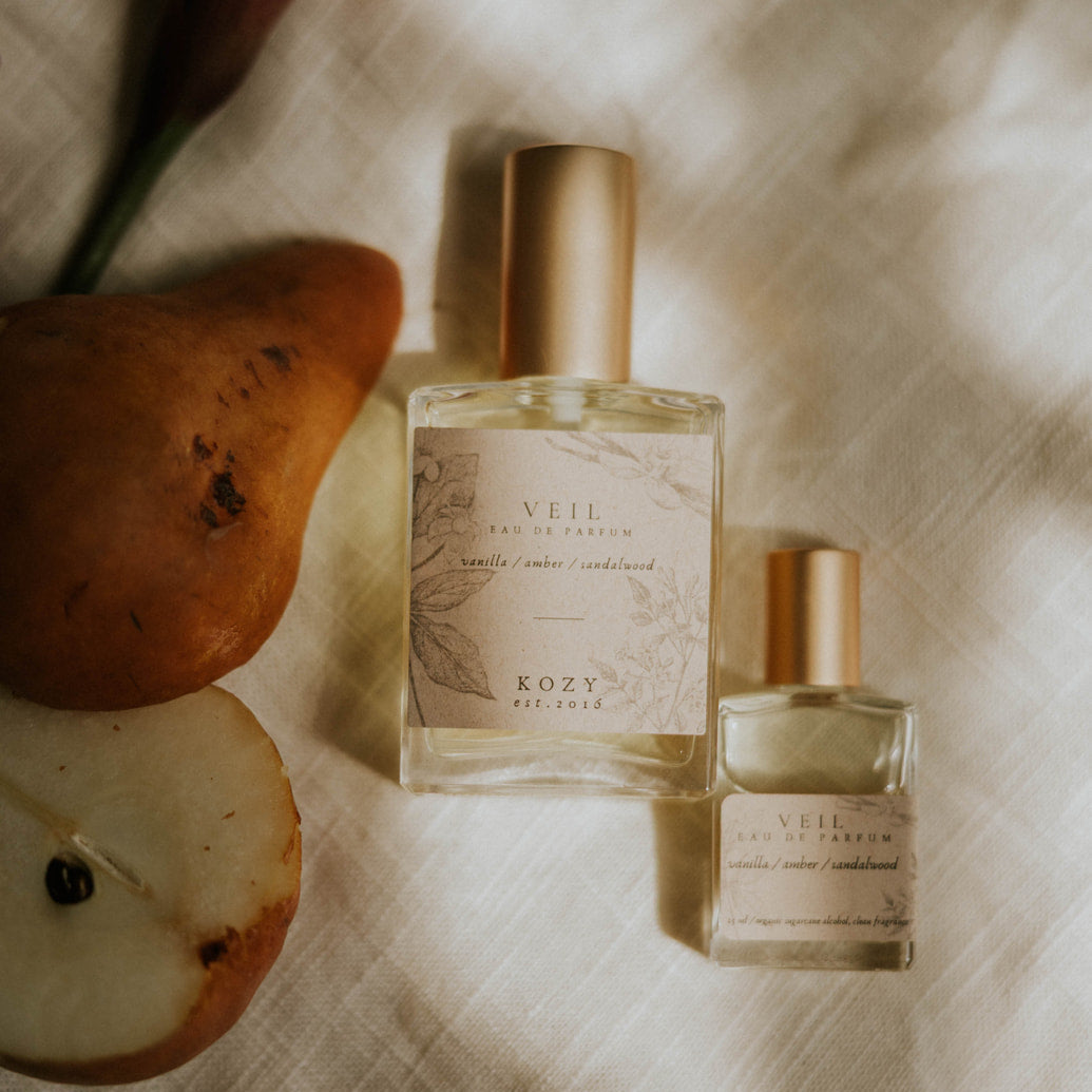 Two small perfume bottles with a pear and flower on a textured surface