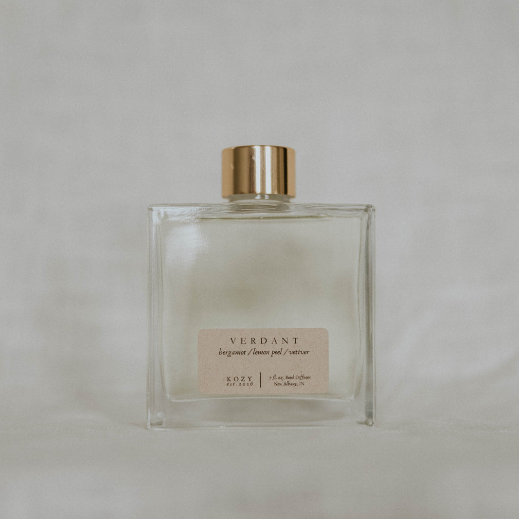 Clear glass perfume bottle with gold cap on a light gray background