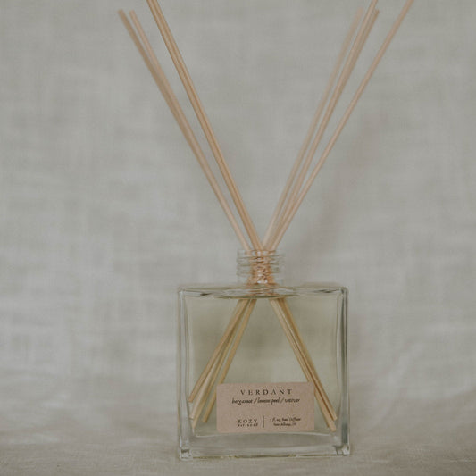 Clear diffuser bottle with wooden sticks on a light gray background