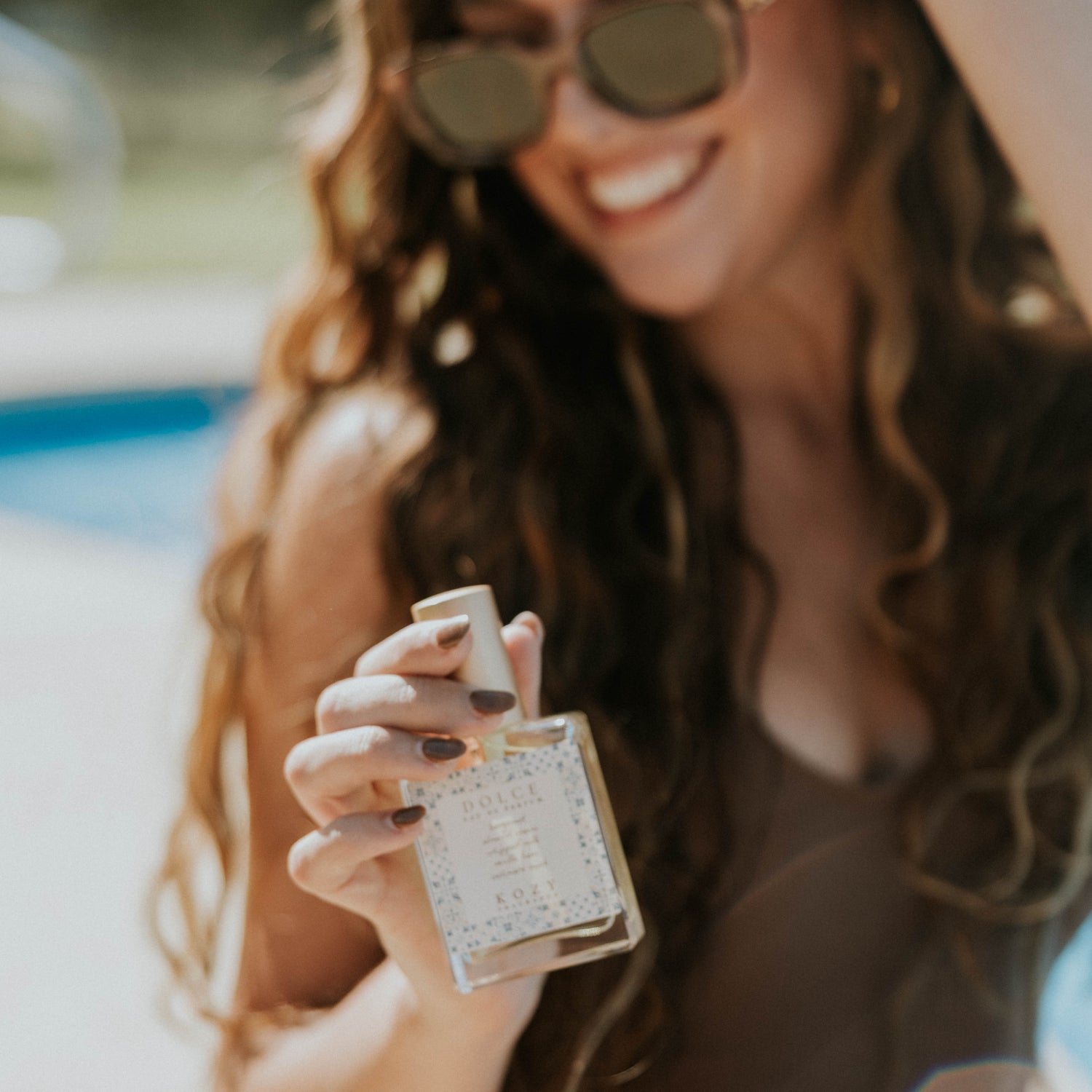 Woman holding a perfume bottle by a pool